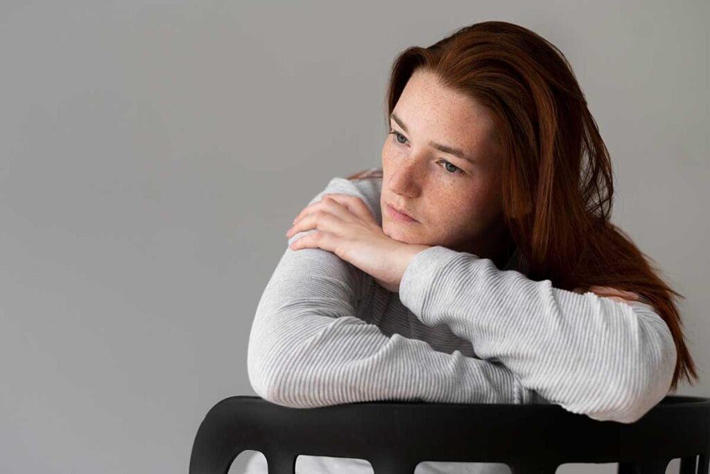 Junge Frau mit traurigem Blick über Stuhllehne